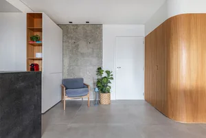 A minimalist entryway featuring a concrete wall, wood furniture, and a white door.