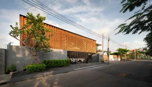 Modern exterior of a house with wooden facade, glass windows, and landscaping.