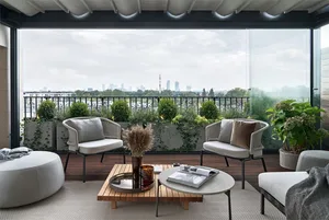 A modern balcony featuring wooden furniture, green plants, and an outdoor view of a cityscape.