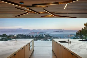 Modern kitchen with marble countertops and minimalist design, featuring stunning mountain view.