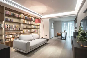 Modern living room with wooden floors, a white sofa, and a red floor lamp.
