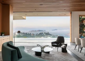 Modern living room featuring minimalist furniture and a large window with a scenic mountain view.