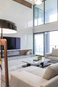 Modern living room with sleek marble coffee table, minimalist furniture, and a large floor-to-ceiling window allowing natural