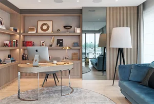 A modern office space featuring a wooden desk and shelves with books and decor.