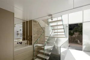 Modern residential interior featuring a glass and wooden staircase with a large window.