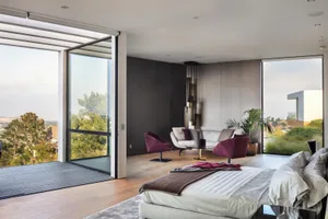 Modern living room with glass walls, wooden floors, and minimalist design.