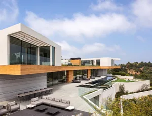 A modern residential space featuring extensive glass, wood, and concrete materials.