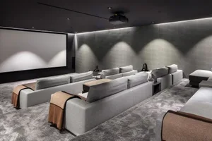A modern, industrial-style home theater room features gray fabric seating and carpeting, creating a sleek and comfortable atm