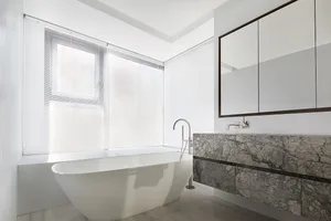 Modern minimalist bathroom featuring a freestanding bathtub and marble countertop.