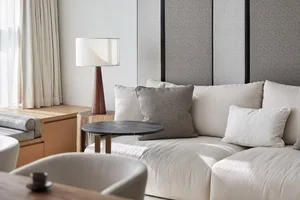 A minimalist living room with a light taupe sofa, cushioned pillows, a textured fabric texture, and a wooden table with a min