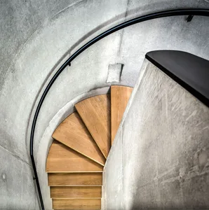 Wooden staircase with a modern design, featuring steel banisters on a concrete wall.