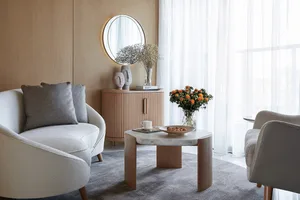 A modern living room with a white sofa, wooden coffee table, and marble flooring. Features include a vase of flowers, decorat