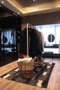 A minimalist interior featuring a clothing hanger with various jackets and shirts.