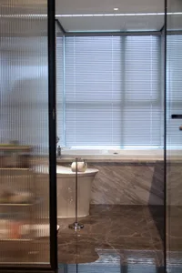 Modern bathroom with marble walls and floor, featuring a freestanding bathtub and a toilet with a roll of toilet paper mounte
