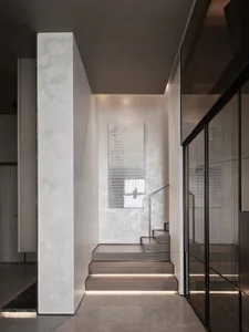Modern interior design featuring concrete and glass stairs leading up to a room with a large window.
