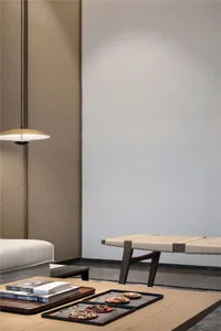 A modern living room featuring a wooden table with rope woven seat, a pendant light, and a minimalist aesthetic