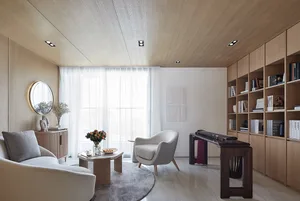 Modern living room with wooden walls and furniture, featuring a round table, armchair, and bookshelf.