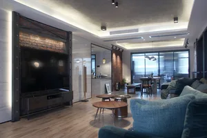 A modern living room featuring wooden floors, brick wall accents, and glass elements.