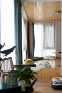 A modern living room with wood flooring, pillows, and curtains, showcasing a cozy and contemporary design.
