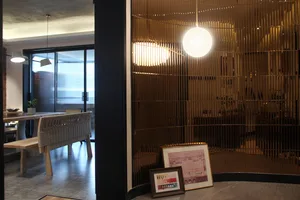 A modern metal dining room with a bench, pendant lights, and framed pictures.