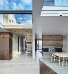 Modern residential interior featuring wood floors, glass walls, metal accents, and marble fireplace.