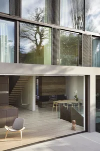 Modern residential space featuring wooden floors, concrete fireplace, and glass walls.