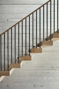 Industrial-style stairs featuring wooden steps and a concrete wall.