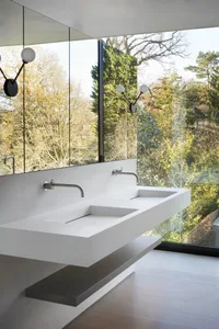 Modern minimalist bathroom with concrete sink and large windows offering a view of greenery outside.