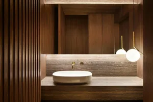 A modern bathroom featuring dark wooden walls and a white sink.
