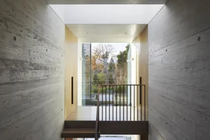 Concrete walls, wooden stairs, and glass wall in a modern interior design.