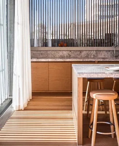 Modern kitchen featuring wooden cabinets and marble countertops with a bar table and stools.