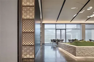 A modern restaurant lobby with marble flooring, stone walls, and glass walls.