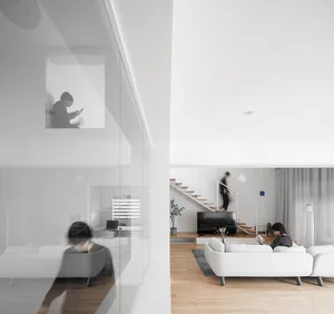 A minimalist white living room with wooden flooring and a white sectional sofa.