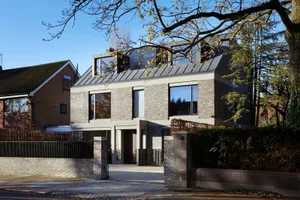Modern brick and concrete exterior of a house with large windows and a metal roof.