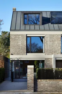 Modern residential exterior with brick facade and large windows.