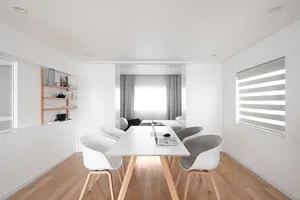 A sleek, modern dining room featuring white furniture and wooden flooring.
