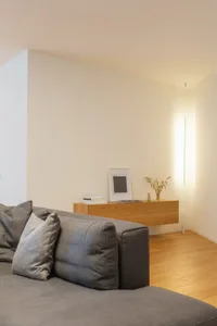 Modern minimalist living room featuring a grey sectional sofa, wooden console table, and tall floor lamp.