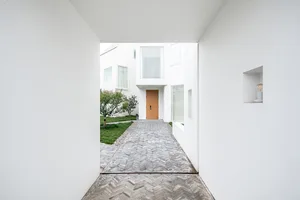 A modern, minimalist courtyard house with concrete materials and a wooden door.