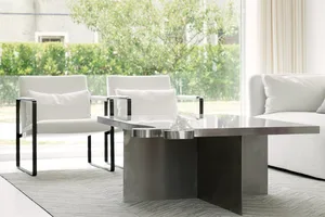 A modern living room with white furniture and a metal coffee table in front of a window.