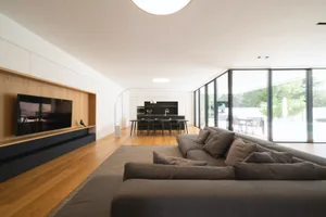 A modern living room featuring a large sectional sofa, a flat-screen TV, and hardwood flooring.