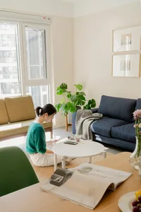 A modern minimalist living room with neutral furnishings, showcasing a blue couch, green chairs, and a white table.