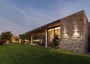 A modern residential house with stone exterior and a lush green lawn.