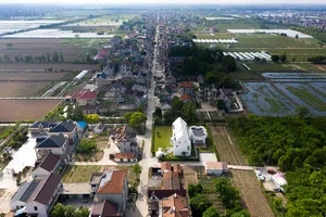 Aerial view of a residential area surrounded by agricultural fields and a road running through the center.