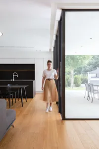 A modern residential kitchen with hardwood flooring, featuring sleek black cabinetry and a spacious dining area leading to an