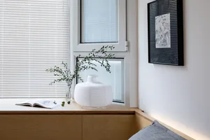 A minimalist interior design featuring wooden accents, a white vase, and greenery.