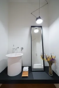 A modern minimalist bathroom with a white sink, mirror, and floor.