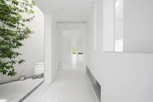 A minimalist white interior space with concrete walls and floors, featuring modern architectural elements and a clean, open d