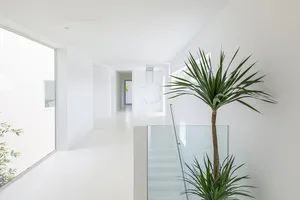 A modern residential interior with white walls and a glass railing.