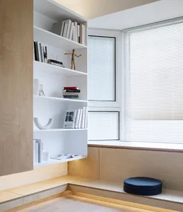 Modern interior design featuring a white wooden shelving unit with books, a sculpture, and a small figurine.