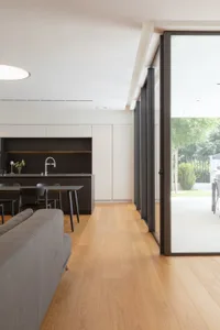 Modern kitchen interior with wooden flooring and black cabinets.